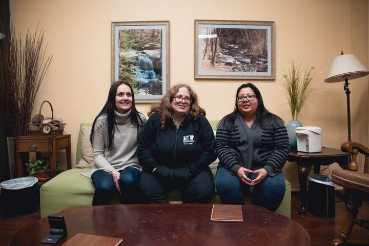 Kate Barnhart sitting with two of her interns. The local college students help her with daily tasks like sorting mail and tutoring.