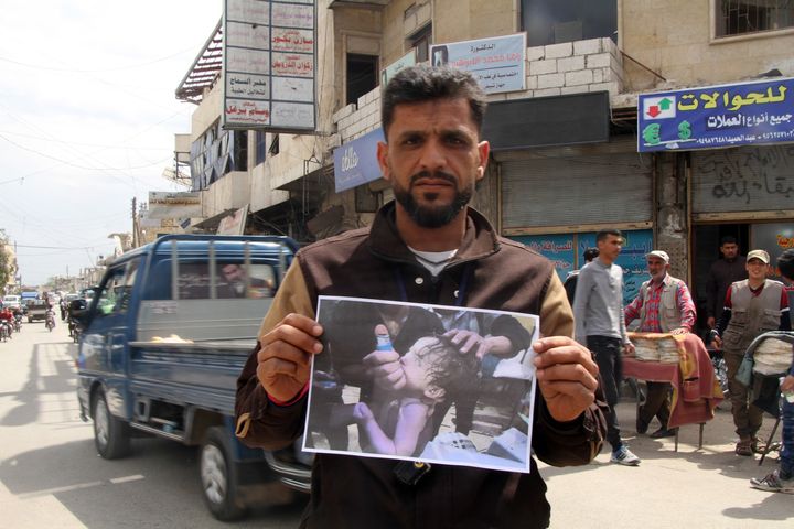 A man holds a photo of a baby victim as he and other demonstrators gather to protest against Assad regime forces' allegedly conducted poisonous gas attack in Duma