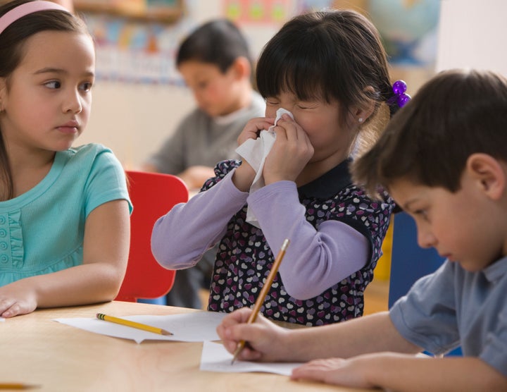 Mixed race girl blowing nose in classroom