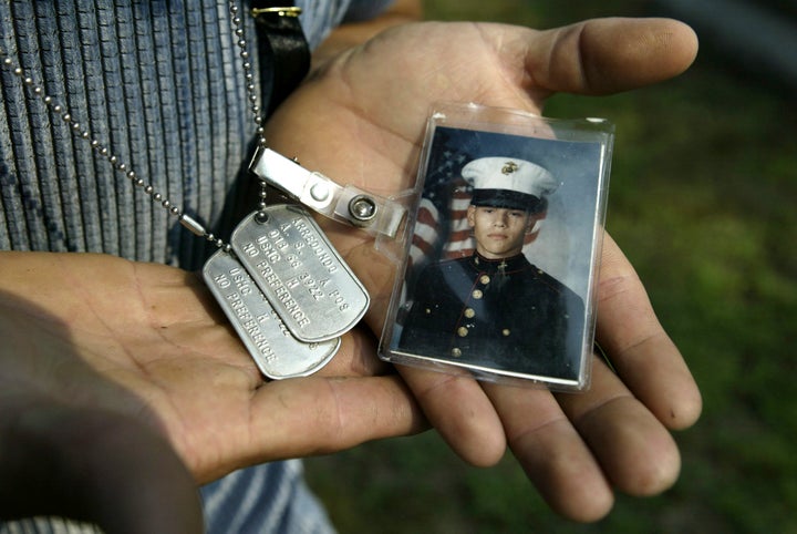 Carlos Arredondo holds dog tags that belonged to his son, Lance Cpl. Alexander Scott Arredondo, while visiting his grave in 2005.