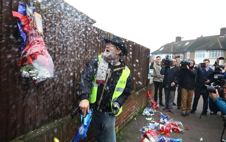 Iain Gordon pulls the flowers down from a fence opposite the house of Richard Osborn-Brooks last week.