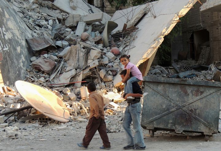 Children walk along a damaged street filled with debris in the Damascus suburb of Zamalka October 3, 2013.