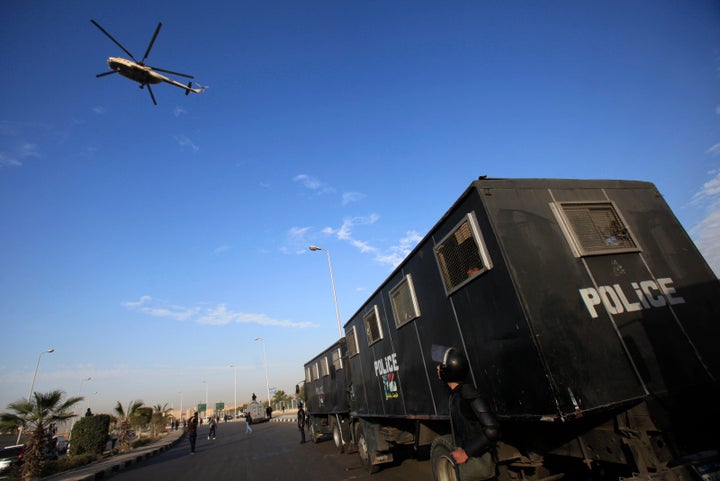 A military helicopter flies over riot police standing guard outside a police academy, where ousted Egyptian President Mohamed Mursi's second trial session was due to take place on the outskirts of Cairo on Jan. 8, 2014. 