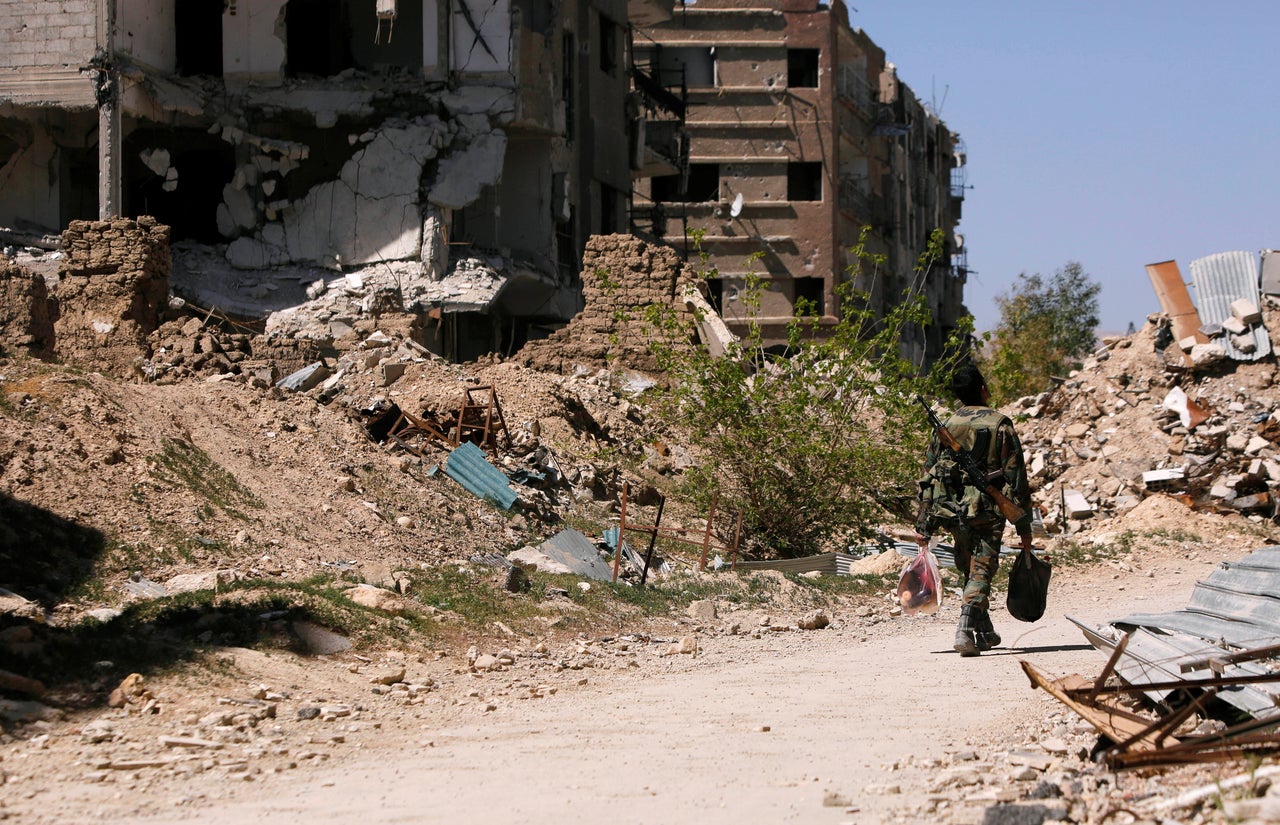 A member of Syrian forces of President Bashar al Assad walks past destroyed buildings in Jobar, eastern Ghouta, in Damascus, Syria April 2, 2018