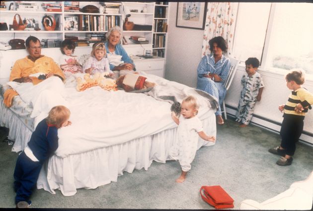 Barbara and George Bush sit in their bed as six of their 14 grandchildren play around them 