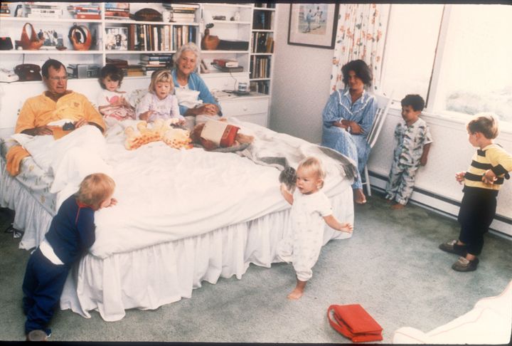 Barbara and George Bush sit in their bed as six of their 14 grandchildren play around them 