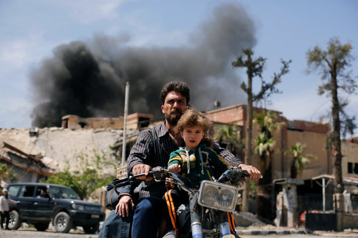 A man and a boy ride a motorbike at the city of Douma in Damascus, Syria, April 16, 2018. 