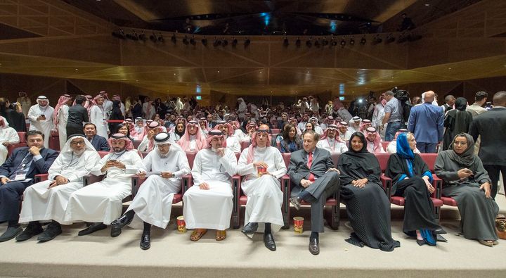 A handout picture provided by the Saudi Royal Palace on April 18, 2018, shows Saudi Information Minister Awwad Alawwad, center, holding a small bucket of popcorn as he attends a test screening at the AMC cinema in Riyadh.