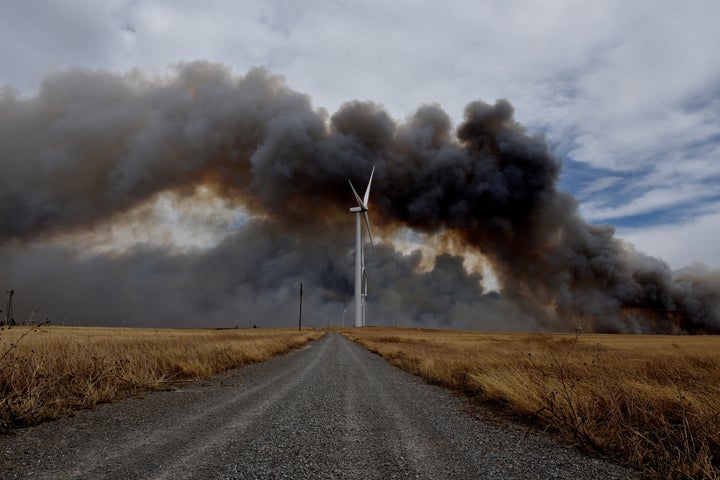 The Rhea fire burns in the distance behind a wind farm near Seiling, Oklahoma.