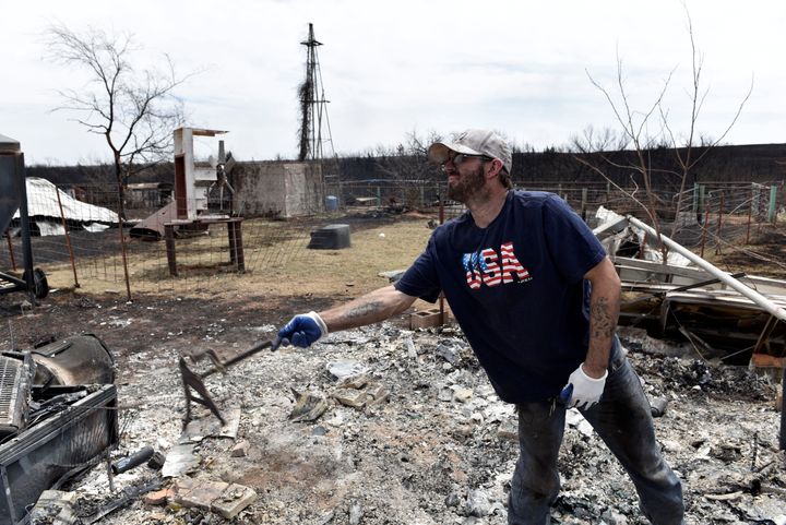 Johnny Lynes sifts through the remains of his parents home that was destroyed by the Rhea Fire near Taloga, Oklahoma.