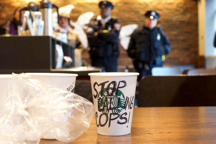 A Starbucks coffee cup with "Stop calling cops!" written on the side sits on a table as police monitor protesters inside a Starbucks in Philadelphia on Monday.