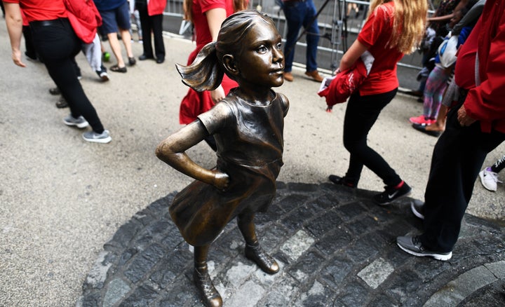 Tourists walk by the Fearless Girl statue in New York City on April 12, 2017.