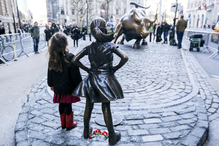 A girl poses with Fearless Girl on March 9, 2017, a day after it was erected.