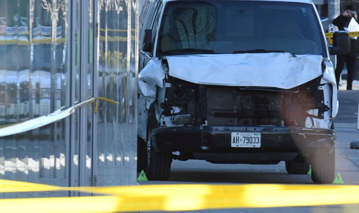A damaged van is seized by police after it struck about two dozen people Tuesday at a major intersection in Toronto.