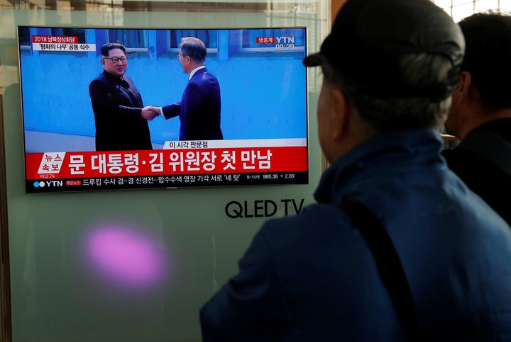 People watch a live broadcast of South Korean President Moon Jae-in shaking hands with North Korean leader Kim Jong Un.