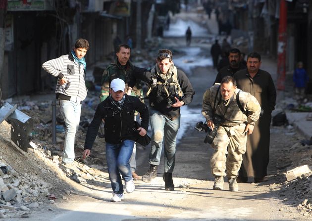 Journalists run for cover in a street in Aleppo. 