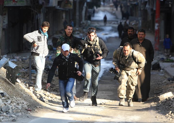 Journalists run for cover in a street in Aleppo. 