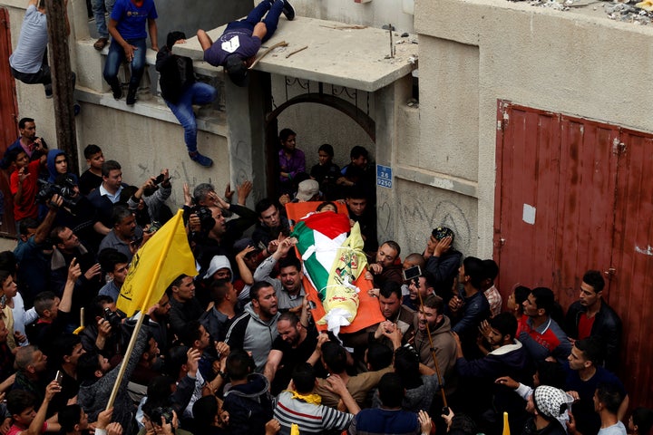 Mourners carry the body of Palestinian Azam Ewidah,15, who was killed at the Israel-Gaza border, during his funeral in the so
