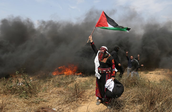 A woman demonstrator holds a Palestinian flag during clashes with Israeli troops at a protest where Palestinians demand the right to return to their homeland, at the Israel-Gaza border in the southern Gaza Strip, April 27, 2018. 