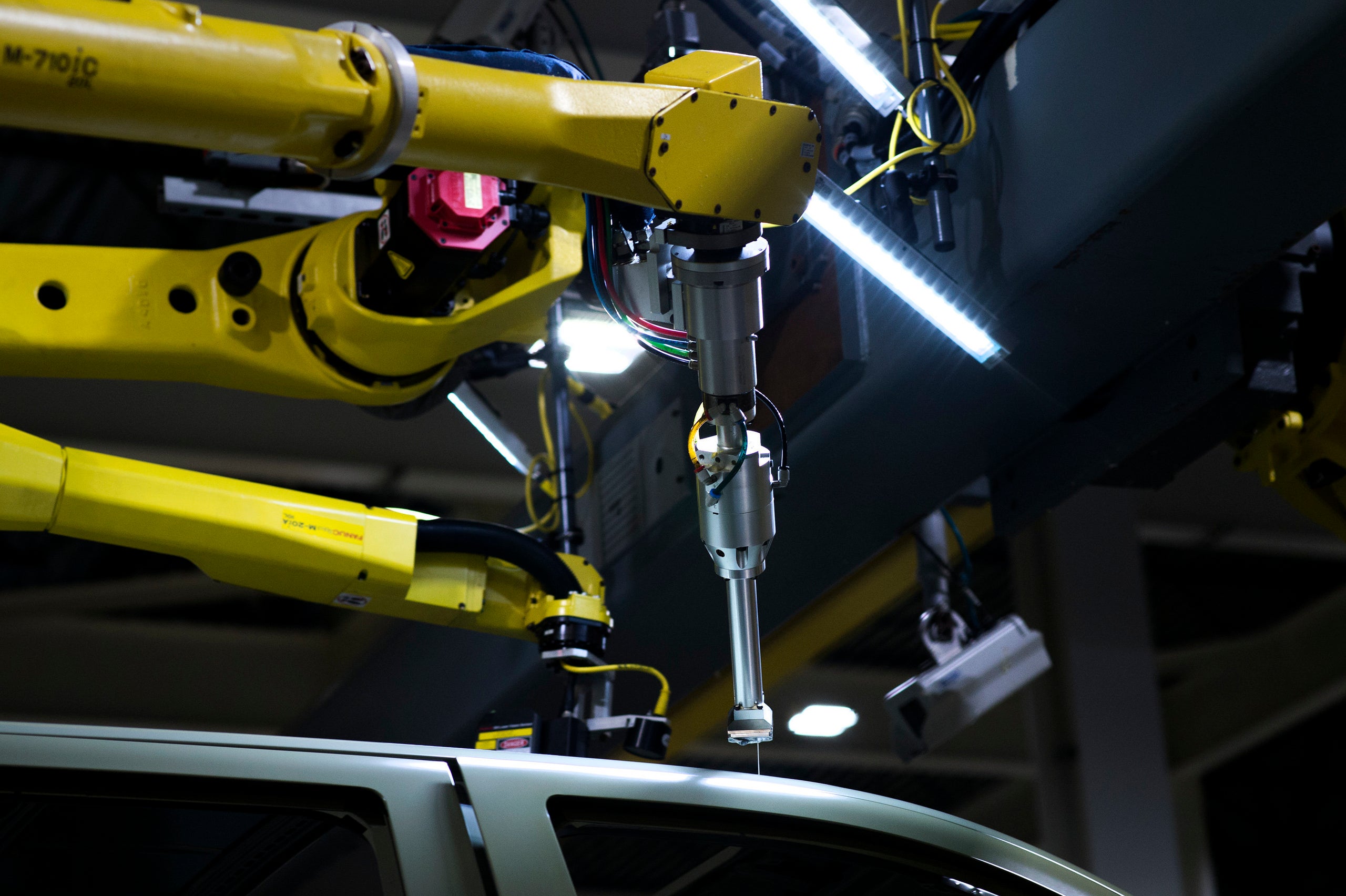 A robot puts a sealant on a pickup truck at the GM Flint plant.