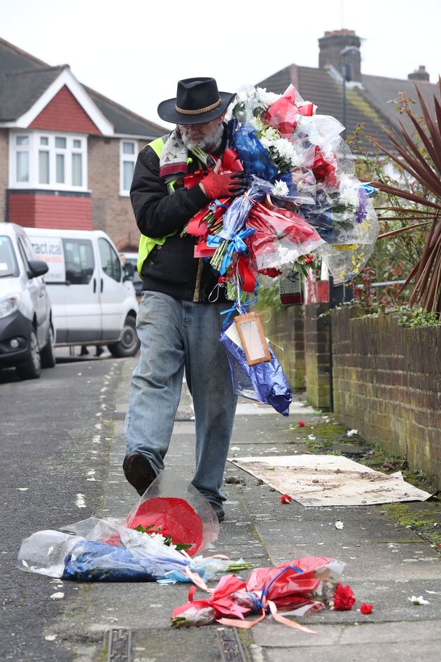 Iain Gordon kicks flowers as he takes them away from the scene near the house of Richard Osborn-Brooks in South Park Crescent in Hither Green