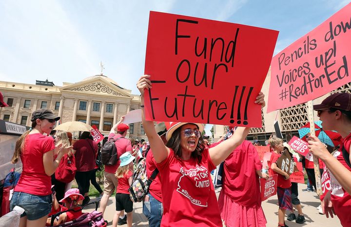 An Arizona teacher holds up a sign in front of the state Capitol during a rally on April 26. Legislation signed by the governor Thursday meets some of their demands.