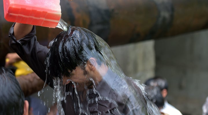 A Pakistani man cools himself off with water collected from a leaking supply line on a hot summer day in Islamabad on June 14, 2016. 