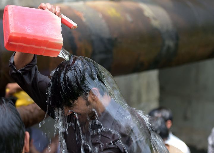 A Pakistani man cools himself off with water collected from a leaking supply line on a hot summer day in Islamabad on June 14, 2016. 