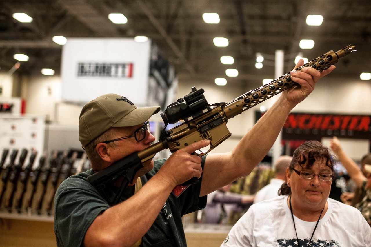Tim Oelklaus of Missouri holds up a display rifle on the expo floor of the annual NRA meeting in Dallas, Texas, on May 4.