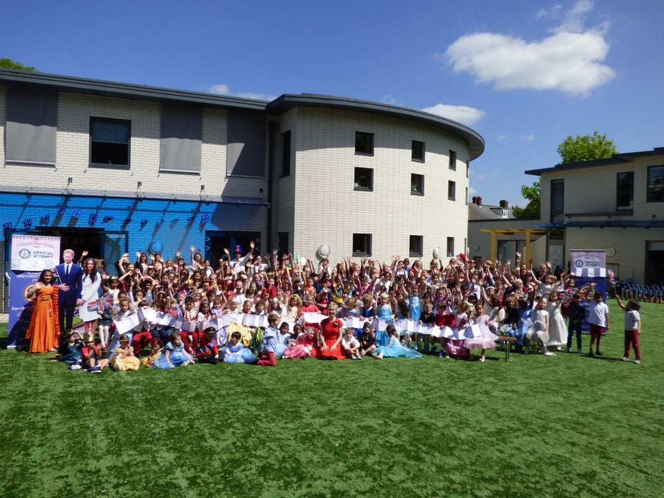 The whole school holding the card they have made for Harry and Meghan. 