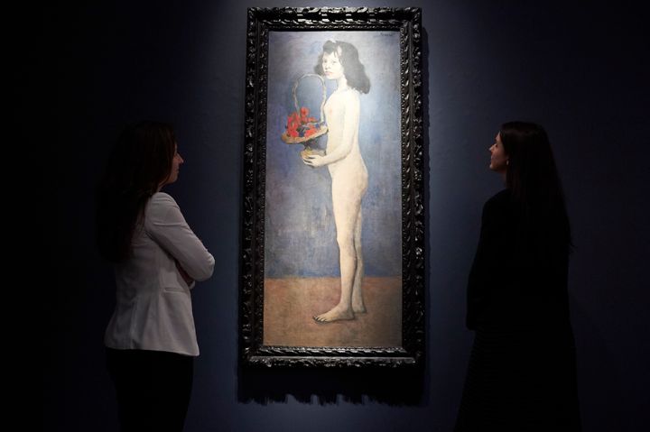 Employees pose with "Fillette a la corbeille fleurie" by Pablo Picasso during a preview for the Peggy and David Rockefeller art collection sale at Christie's auction house in London on Feb. 21, 2018. 