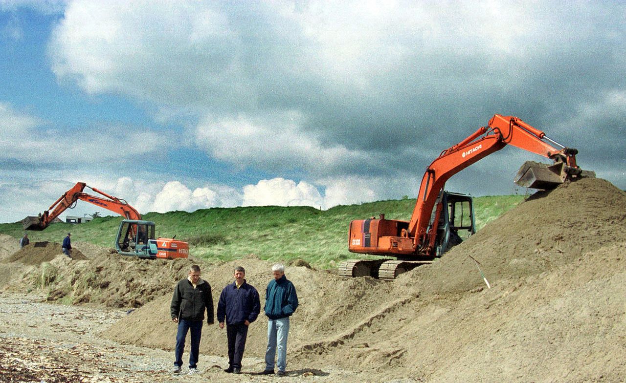 Relatives of Jean McConville stand between the diggers during the final hours of the search for her remains in Templetown Beach near Dundalk