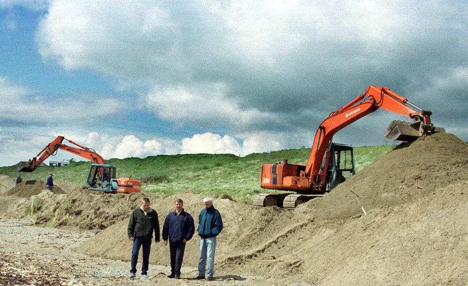 Relatives of Jean McConville stand between the diggers during the final hours of the search for her remains in Templetown Beach near Dundalk