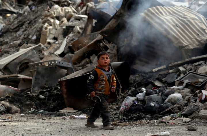 A Syrian child walks past destroyed buildings in the northern Syrian city of Raqa, on January 11, 2018, after a huge military