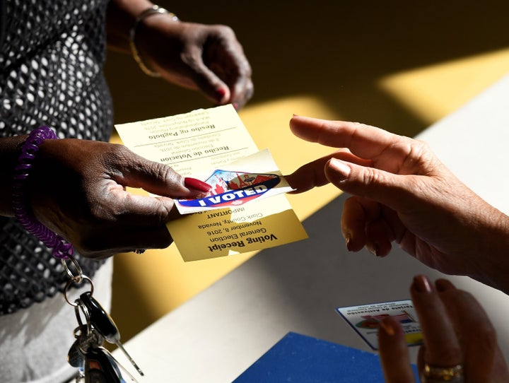 A poll worker gives a voter a Las Vegas Strip-themed "I Voted" sticker at a polling station at Cheyenne High School on Electi