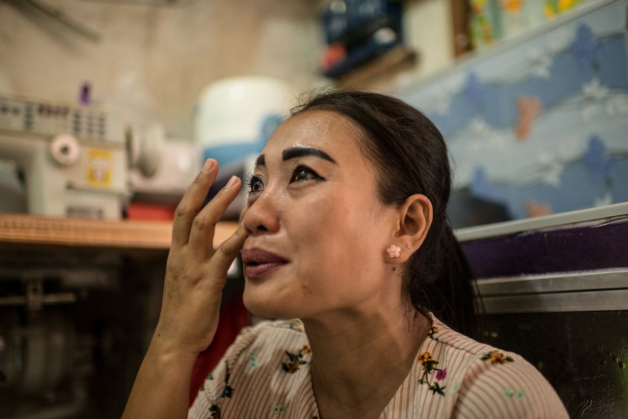 Istiy cries inside her tiny rental room while speaking of the two daughters she left behind in her village.