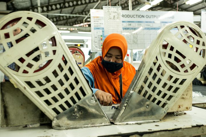 A worker sits at a machine for stitching buttons on jackets and pants, at Pan Brothers garment factory in Tangerang, Jakarta.