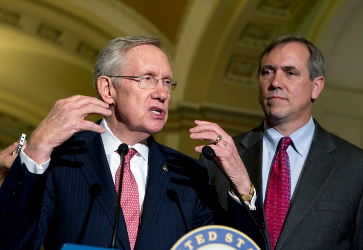 Then-Senate Majority Leader Harry Reid (D-Nev.) speaks to reporters after Senate luncheons as he is accompanied by Sen. Jeff