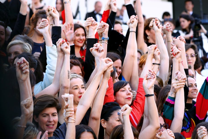 Women join hands as they stand on the steps of the Palais des Festivals.