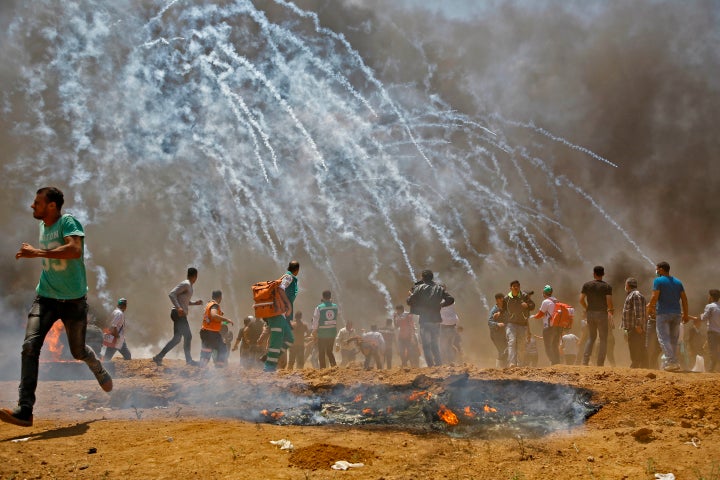 Palestinians run for cover from tear gas during clashes with Israeli security forces near the border between Israel and the G