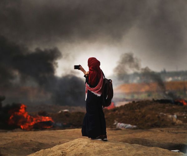 A Palestinian woman documents the situation at the border fence with Israel in Gaza City, Gaza. 