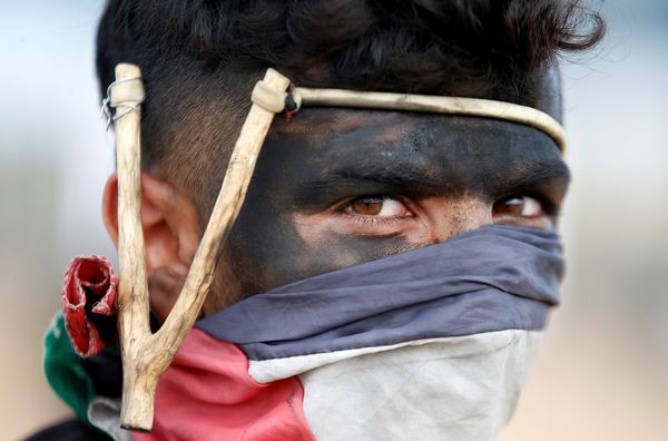 A Palestinian demonstrator with a slingshot looks on during the protests.&nbsp;