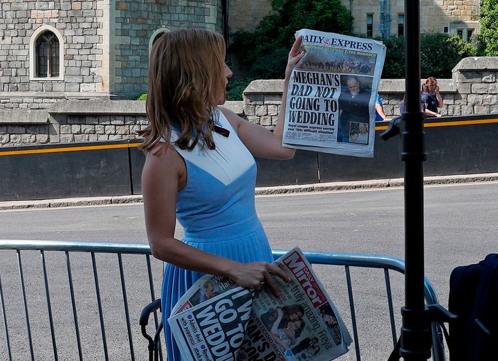 A CNN reporter holds up copies of British newspapers leading with a story on Thomas Markle outside Windsor Castle on May 15.