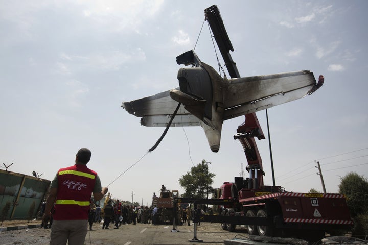 Iranian firefighters relocate the remains of a plane near Tehran's Mehrabad International Airport after a crash in 2014.