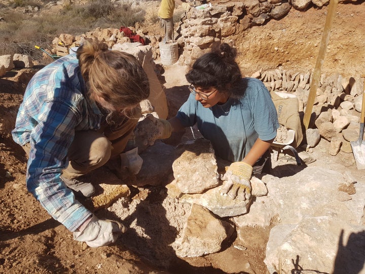 Two volunteers, Fran and Amneh, build a stone roundhouse to house visitors.