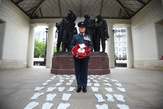 Flight Lieutenant Nigel Painter holds a wreath as he stands among 53 pairs of flying gloves at the Bomber Command Memorial in London's Green Park 