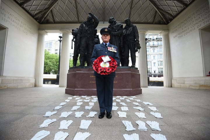 Flight Lieutenant Nigel Painter holds a wreath as he stands among 53 pairs of flying gloves at the Bomber Command Memorial in London's Green Park 