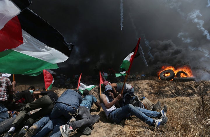 Palestinian demonstrators take cover from Israeli fire and tear gas during a protest against U.S. embassy move to Jerusalem.