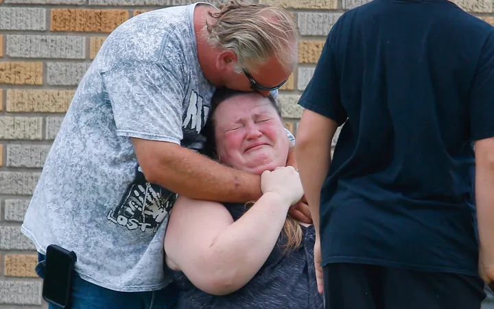 A man hugs a woman outside the Alamo Gym where parents wait to reunite with their children.