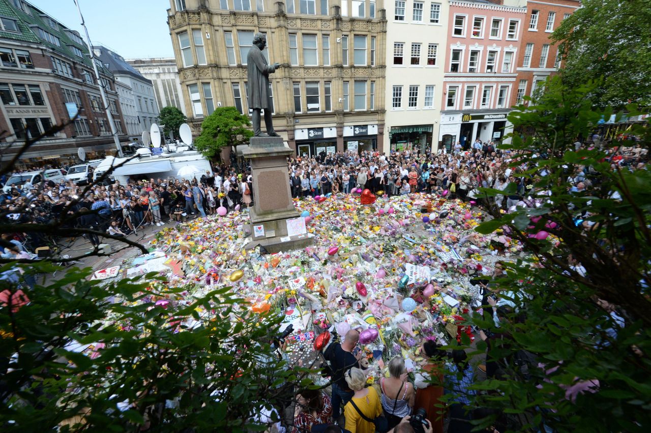 Crowds look at the floral tributes after a minute's silence in St Ann's Square, Manchester.